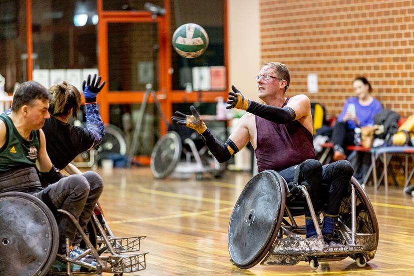 Two people in wheelchairs throwing a ball upwards