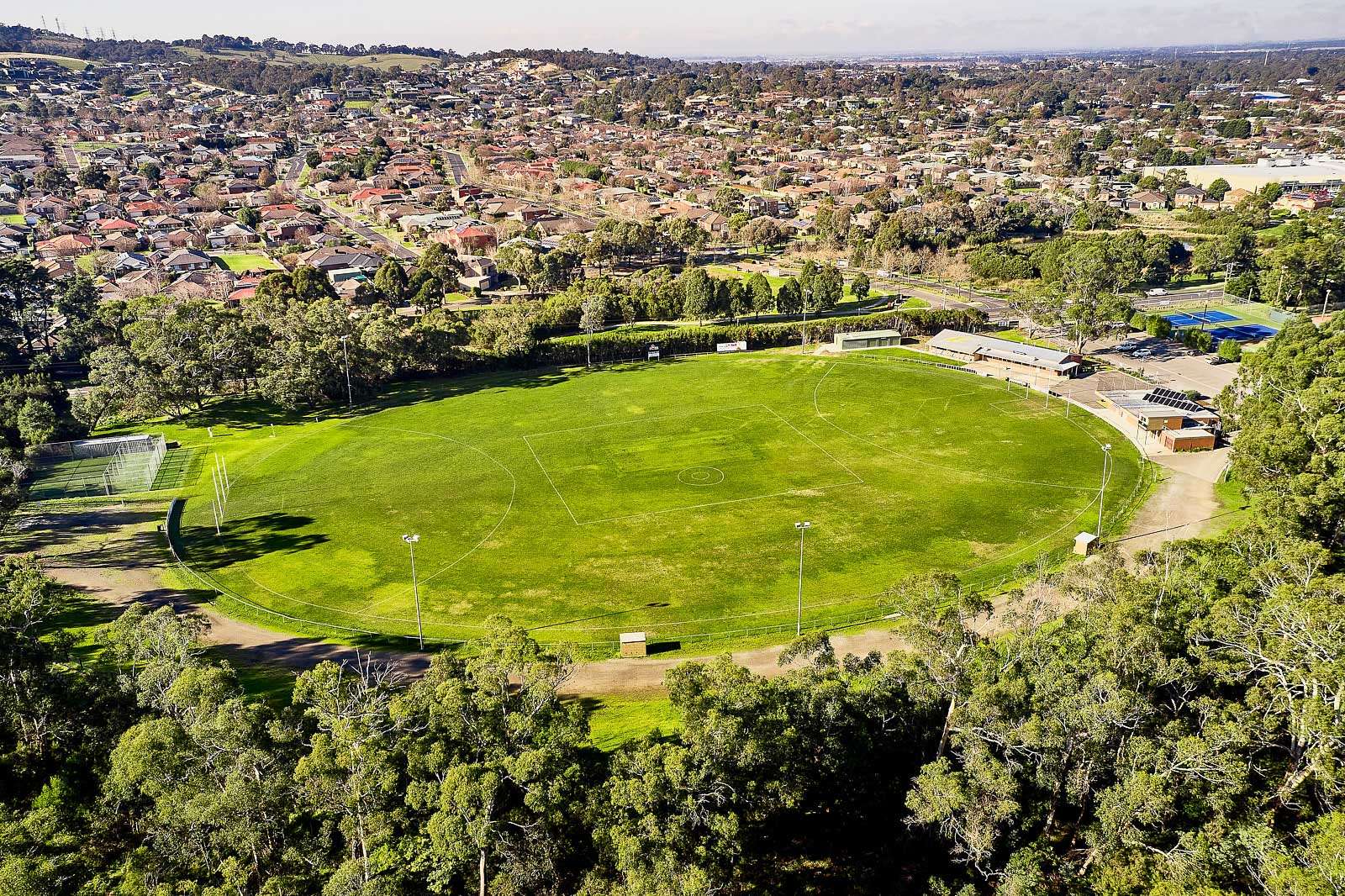 A large green field surrounded by trees.