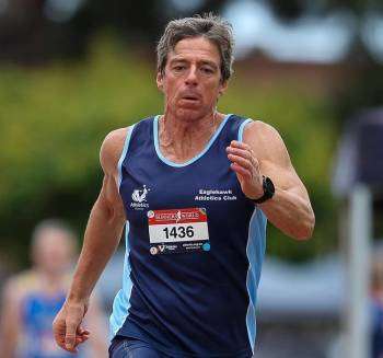 A man running in a dark blue singlet featuring a number on the front