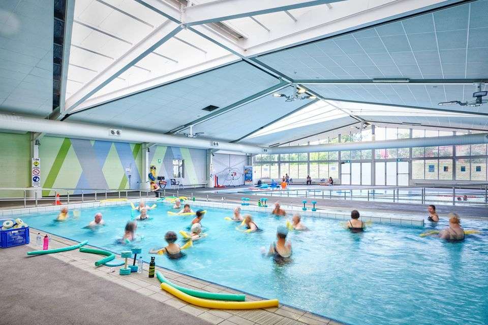 An indoor inground level swimming pool with a group of swimmers doing water aerobics.