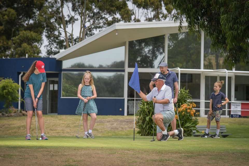 A group of people playing golf on green grass.