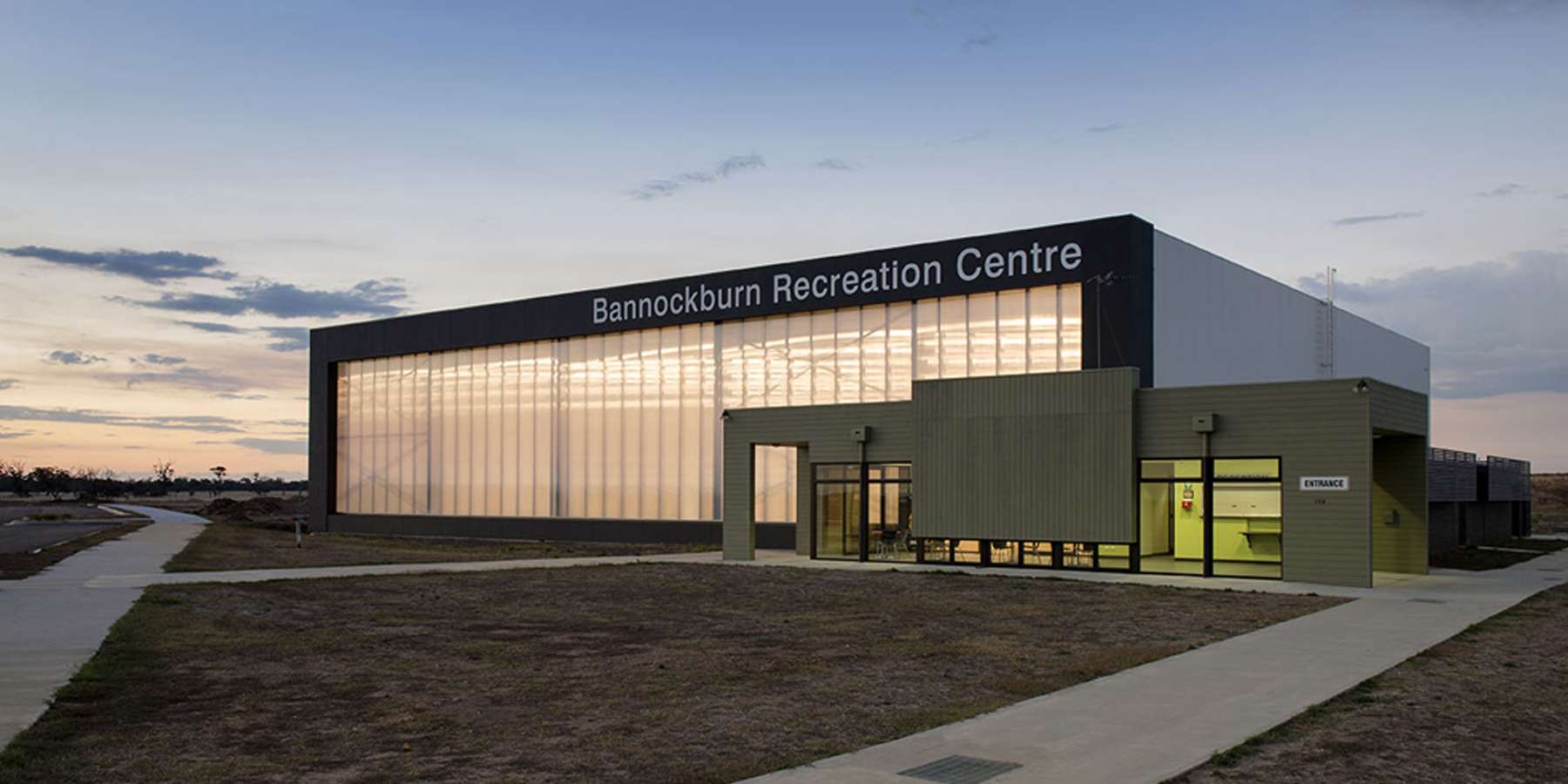 Modern building with large glass windows and a sign reading "International Research Centre," set against a twilight sky.