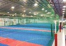 Indoor sports facility with multiple colorful courts, divided by nets, under bright lights. Ideal for various games and activities.