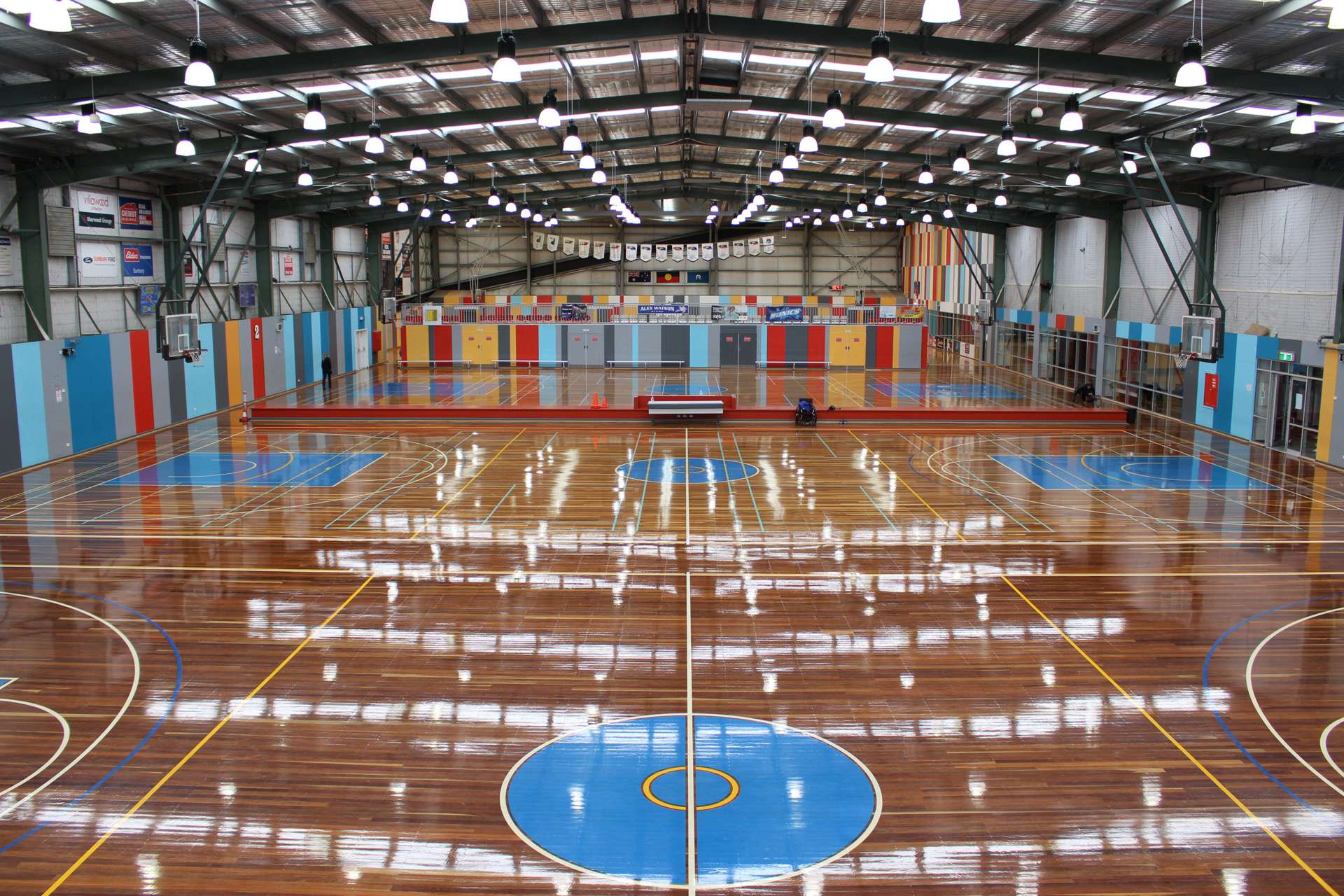 a large stadium overlooking basketball courts with bright lights.