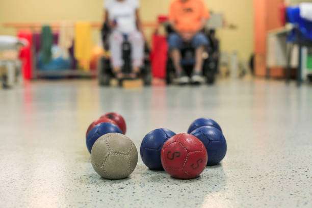 Boccia balls on a smooth floor, with people in the background sitting in wheelchairs.