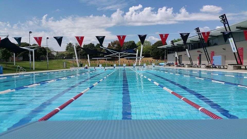An indoor inground level swimming pool with multiple lanes divided by ropes.