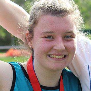 A woman smiling at the camera with a medal around her neck
