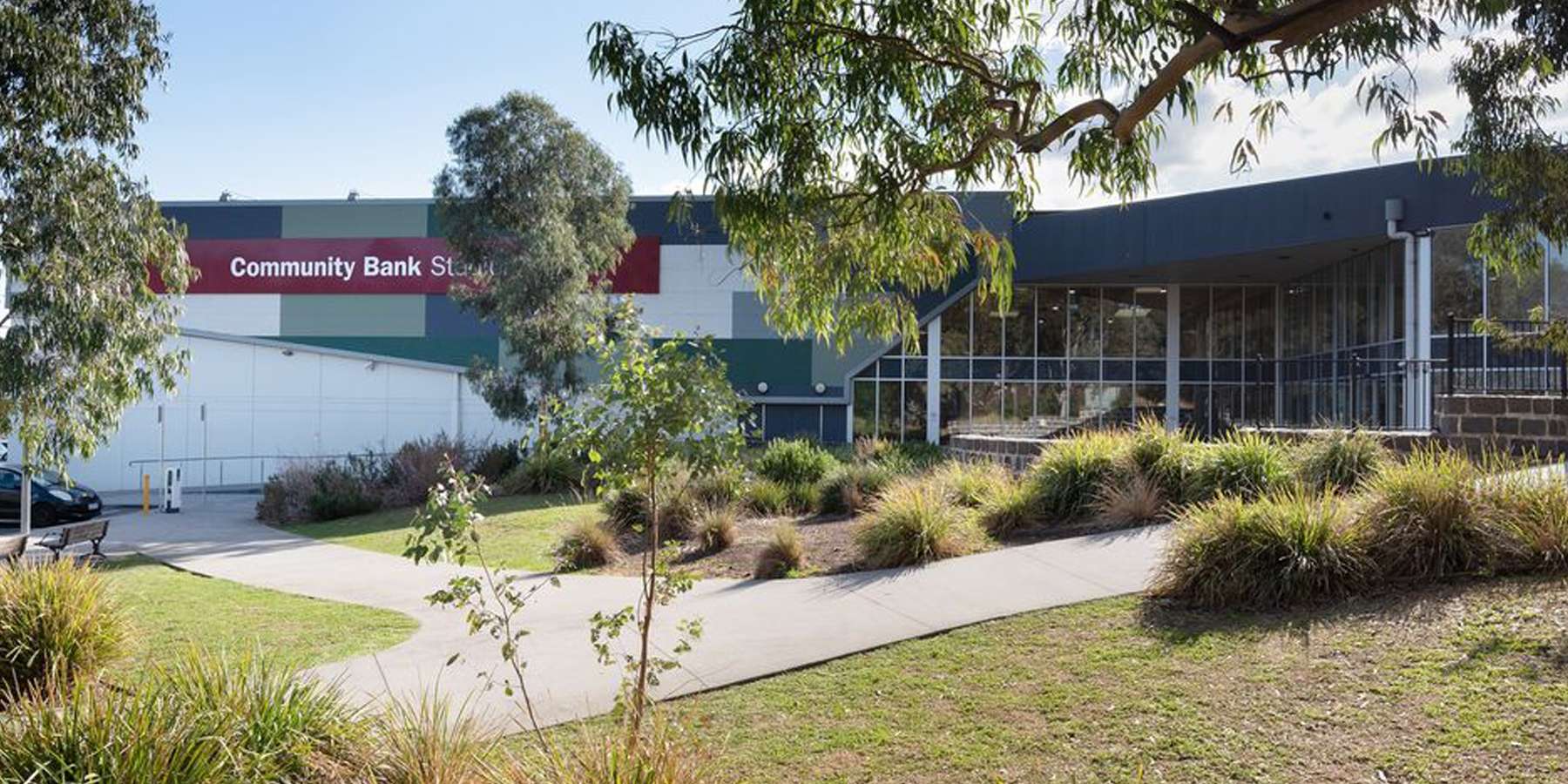 Exterior view of a modern community bank building surrounded by greenery and a landscaped path.