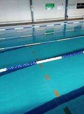 A clean, indoor swimming pool with clear blue water, marked lanes, and a bright environment showcasing swimming lanes and wall signage.