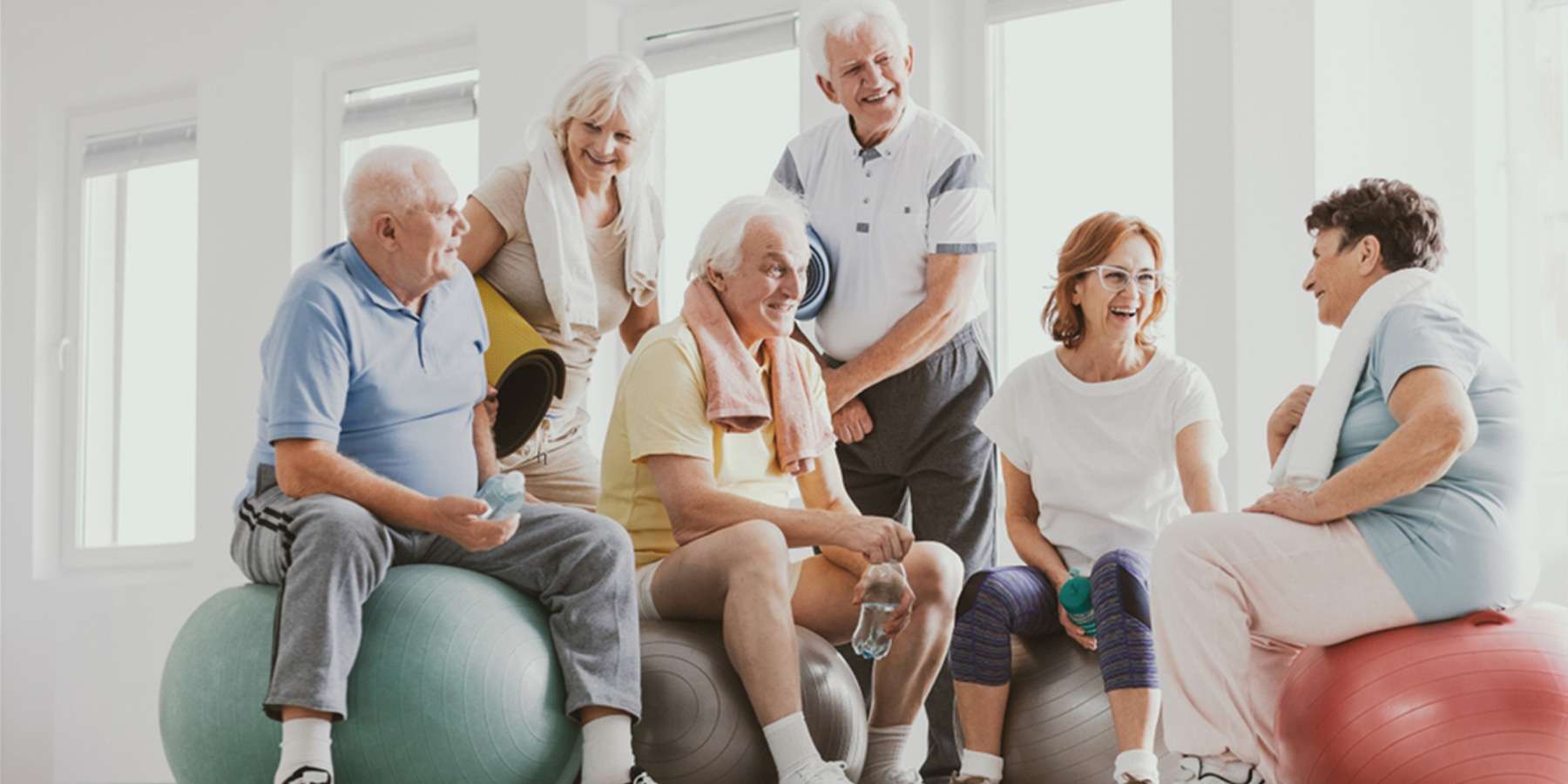 a Group of elderly people smiling and sitting on exercise balls