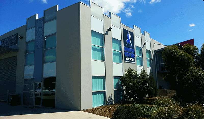 A medium sized grey building with many windows surrounded by trees.