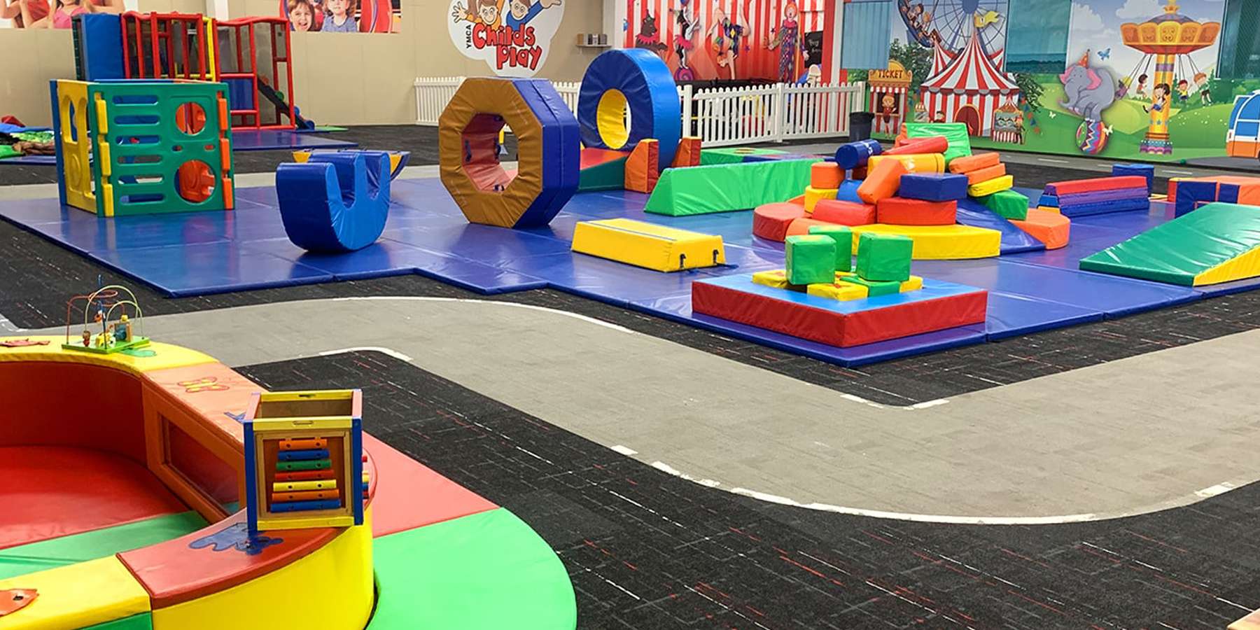 A colorful indoor play area filled with soft blocks, climbing structures, and a winding pathway, designed for children's play and exploration.