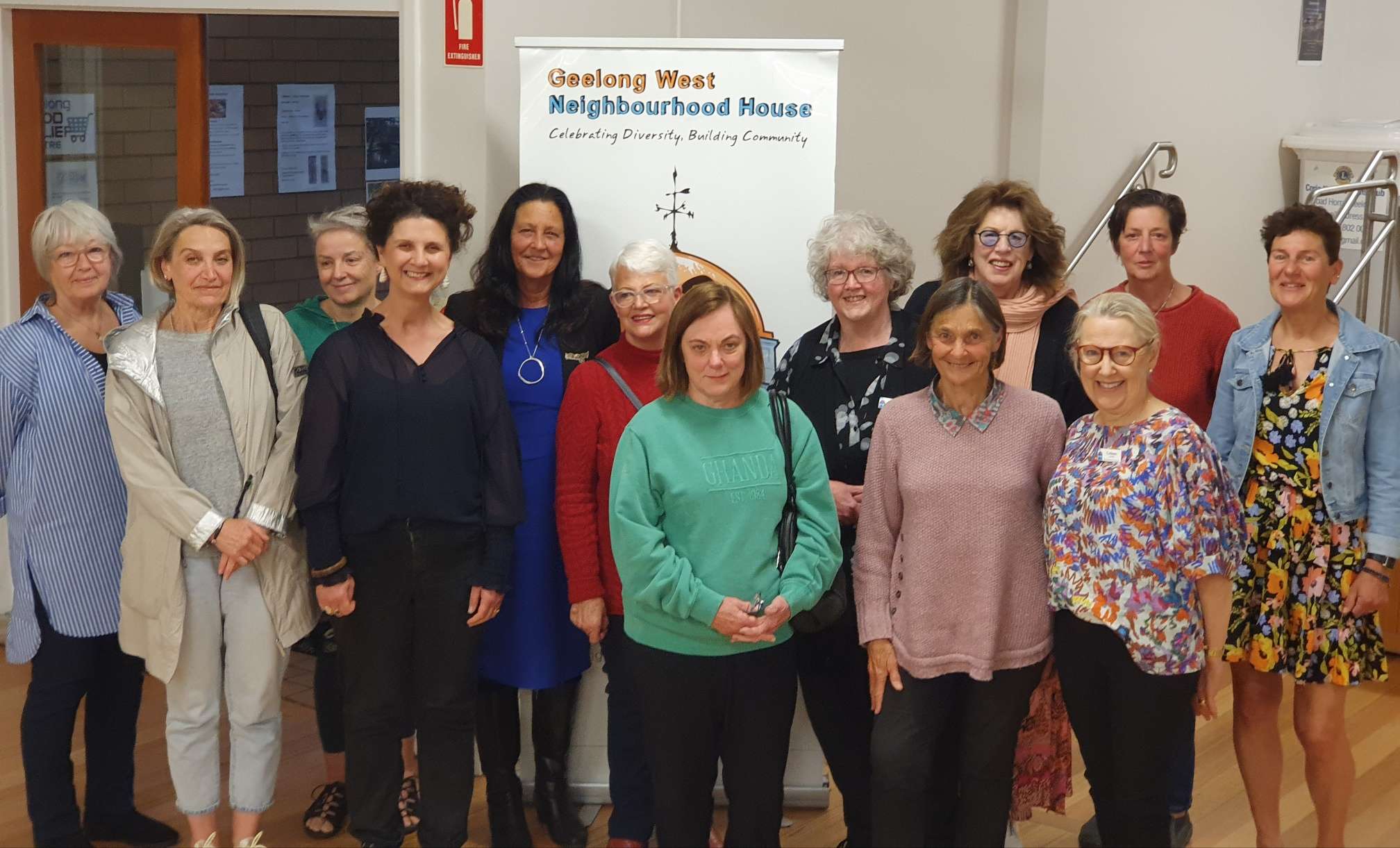 A group of males and females inside a large room with cream walls.