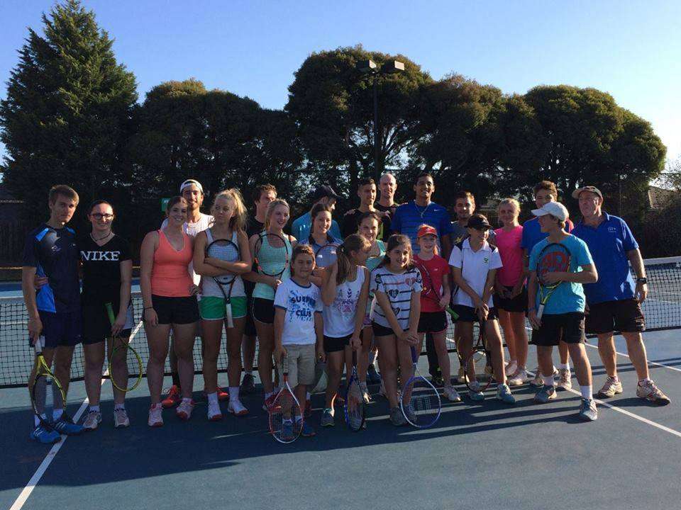 A group of people on a tennis court in a group photo.