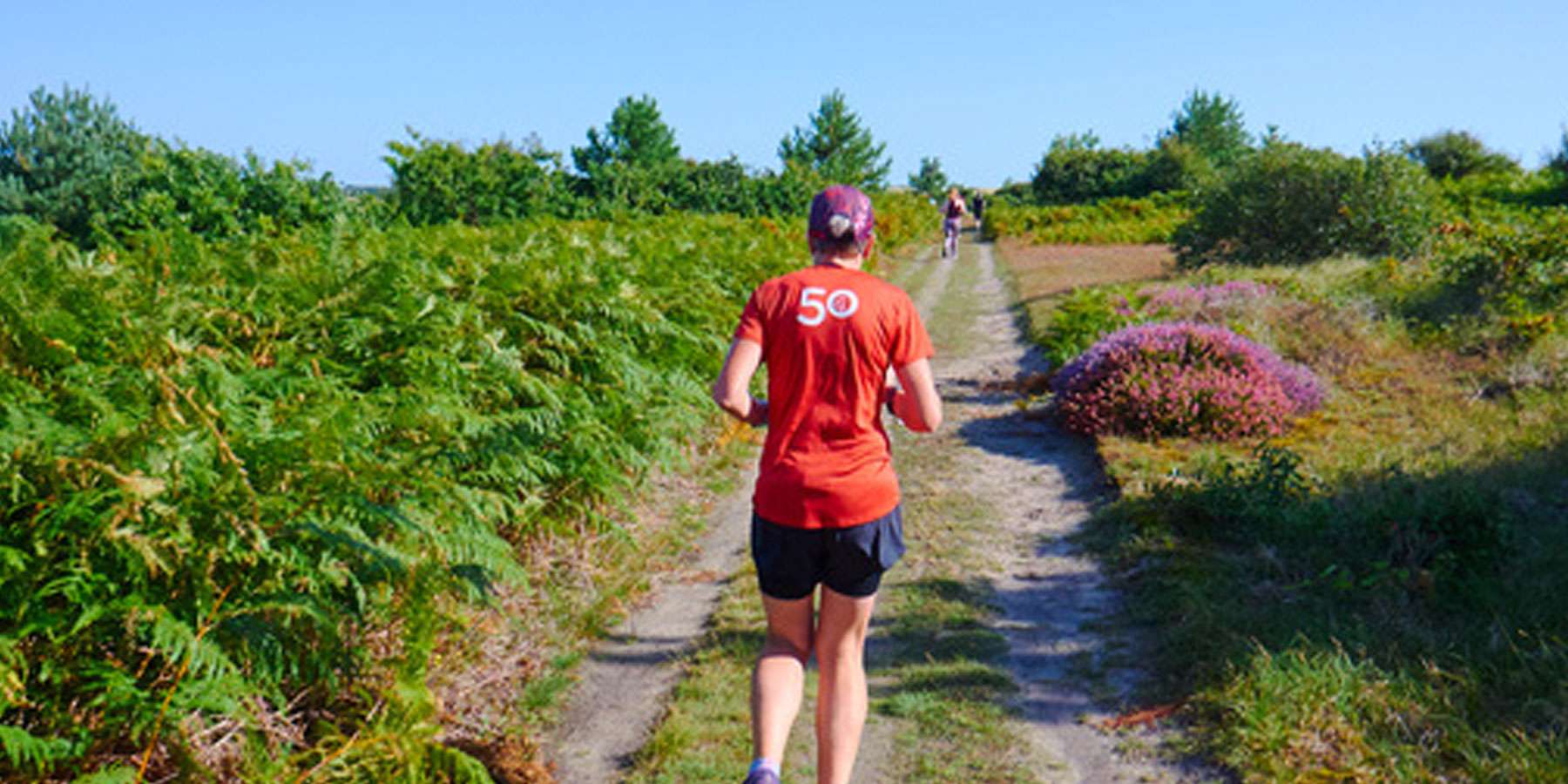Image taken from behind a runner on a dirt road in an open space