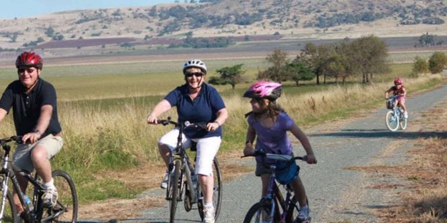 Open space with hills in the background and people riding bikes on a footpath