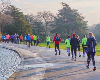 Image taken from behind a group of runners on a footpath with a lake to the left