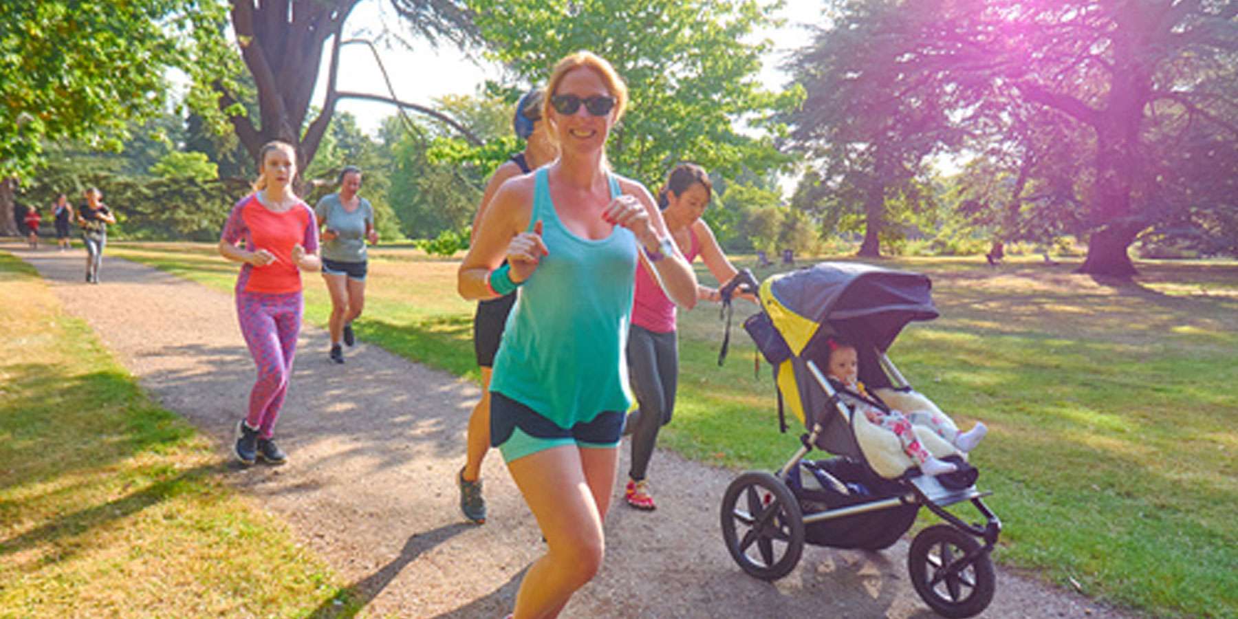 Image of a lady running with other people. There is a lady running with a pram also.