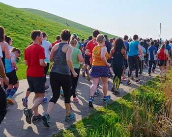 Image taken from behind a group of people running on a footpath in a green space