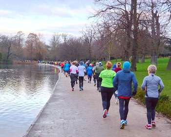 Image taken from behind a group of people running on a footpath with a lake to the left