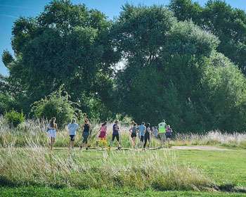 Image of people running in the distance in an open space with trees in the background