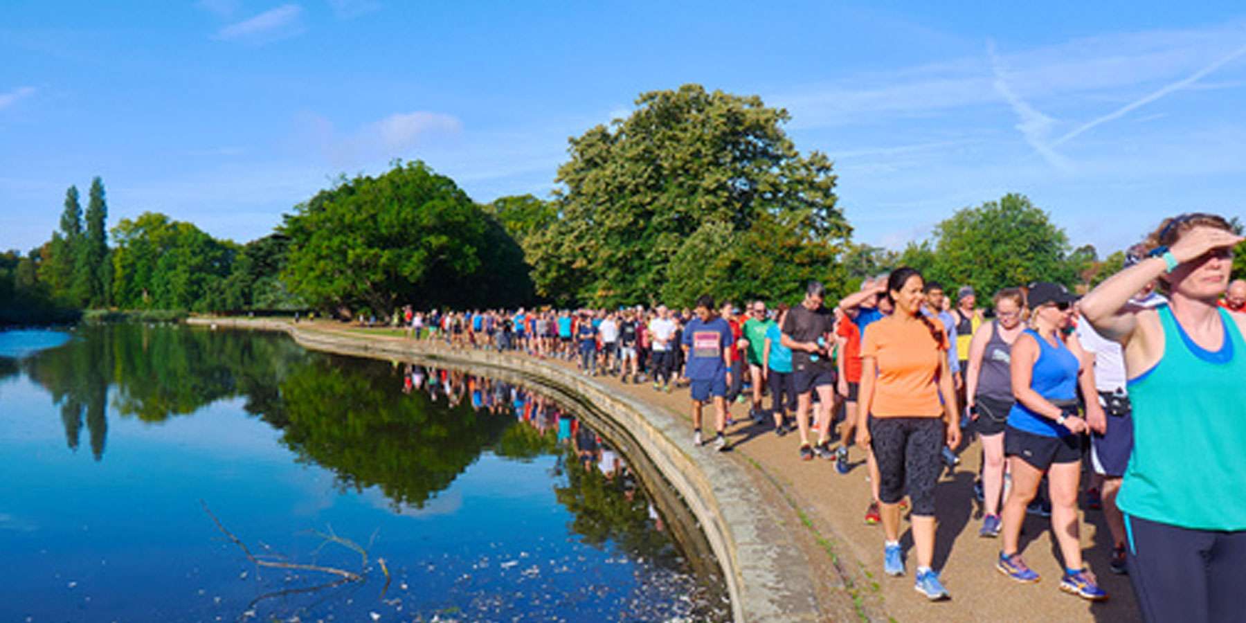 Group of people walking on a footpath with a lake to the left
