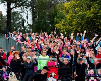 Image of a group of people standing on a bridge with their arms in the air and smiling