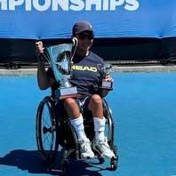 a wheelchair tennis player in a wheelchair with trophies.
