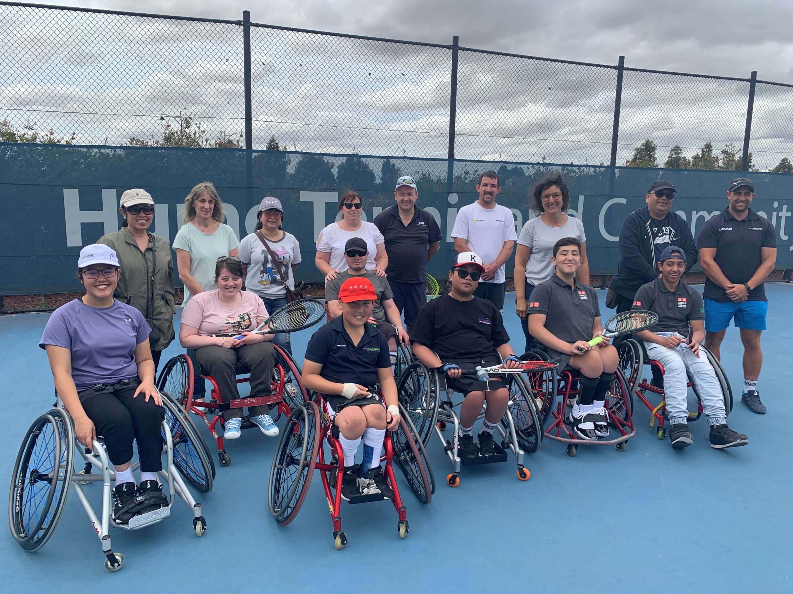 A photo of a group of participants in wheelchairs on a tennis court