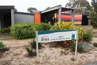 A modern building with colorful accents surrounded by greenery, featuring a sign that reads "Japara Living & Learning Centre."