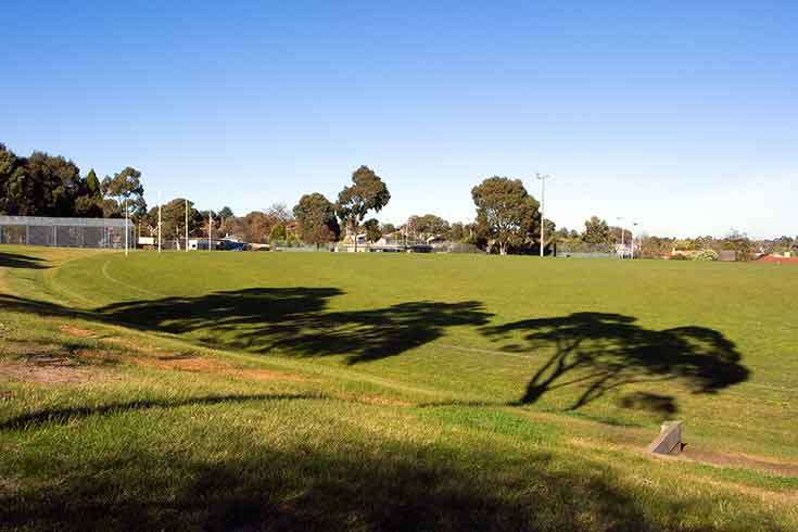 A green oval with goal posts and club rooms to the left