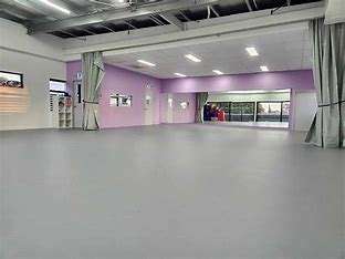 Image displays empty kreationz cheer and dance studio. The floor is grey in colour, and some of the walls are purple