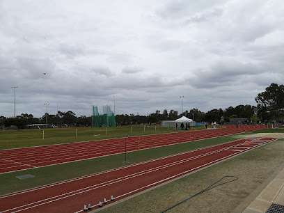 Photo displaying an athletics running track, a sand pit for athletics like long jump, grassy areas, in this photo the sky is overcast