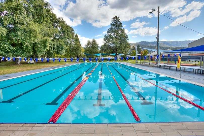 An indoor inground level swimming pool with multiple lanes divided by ropes with multi coloured flags above.