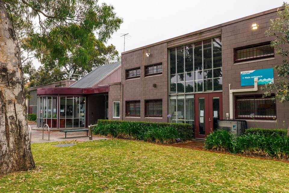 A large brown brick double storey centre surrounded by grass and trees.
