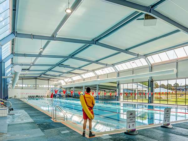 An indoor inground level swimming pool with multiple lanes divided by ropes..