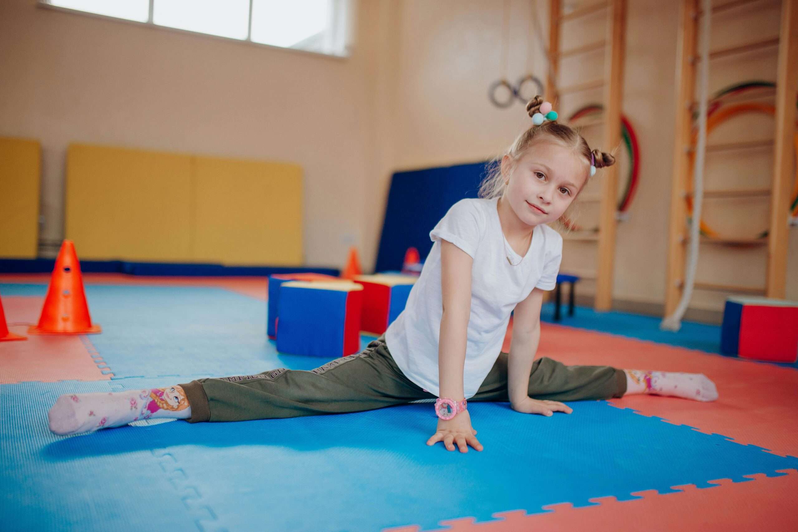 A young girl doing the splits at a gymnastics class