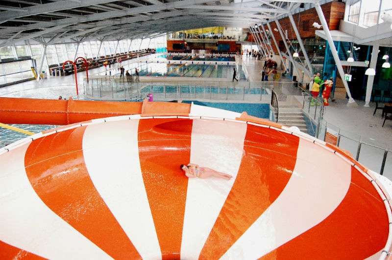 Open red and white water slide bowl overlooking the swimming pool water slide elevated above.