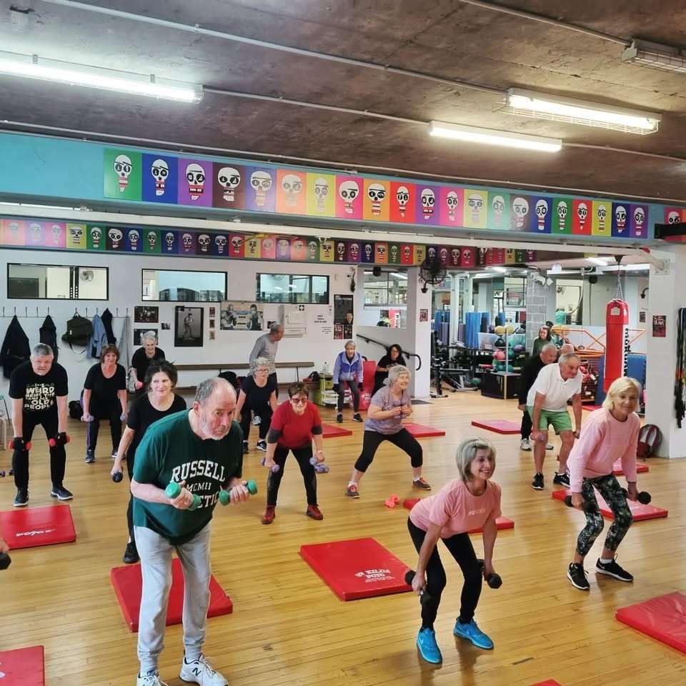 a group of adults doing a fitness class indoors.
