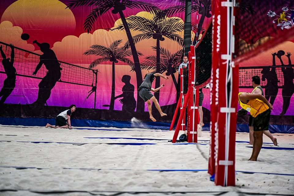 A large volleyball area on sand with red poles holding the volleyball nets.