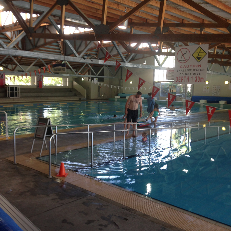 An indoor inground level swimming pool with multiple lanes divided by ropes.